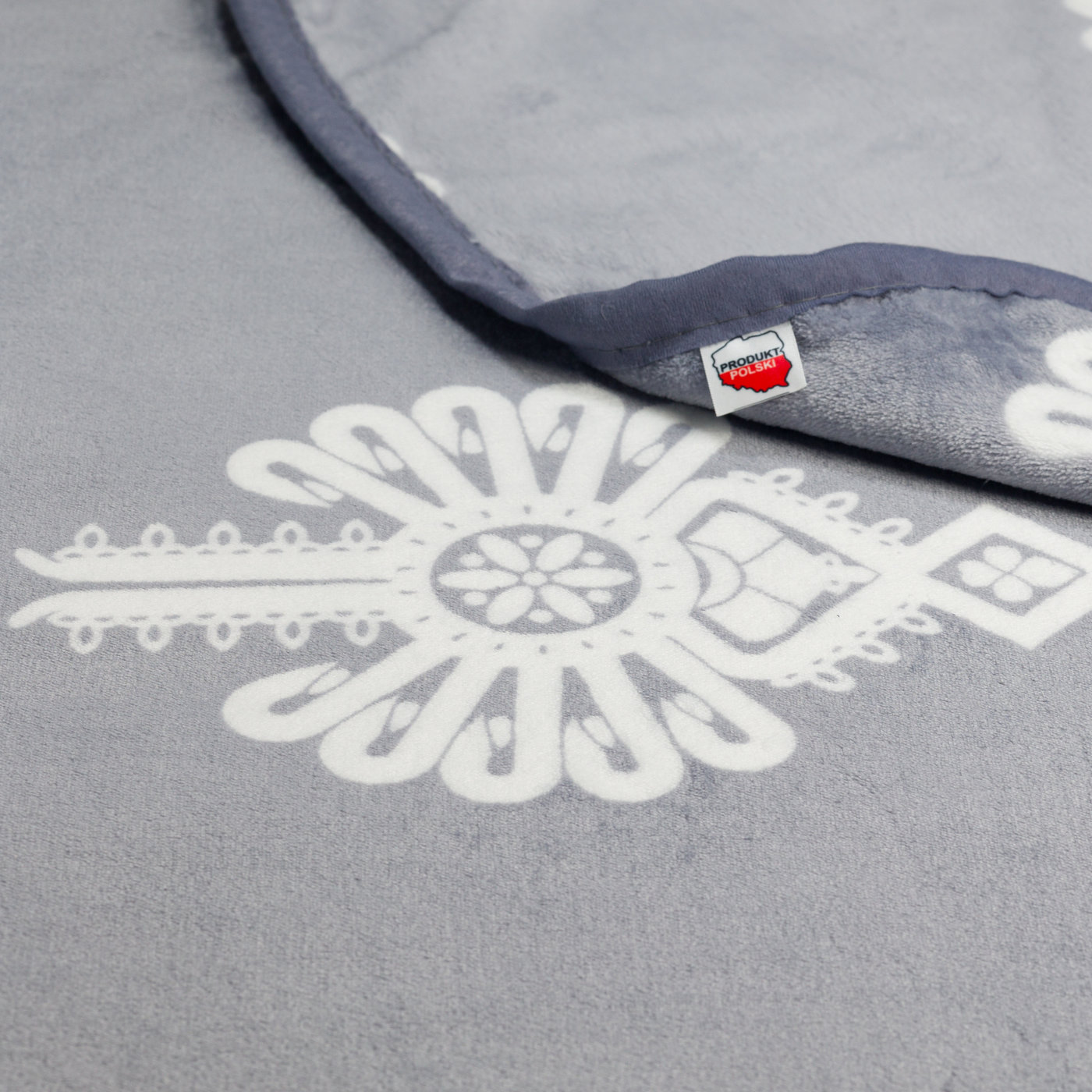 Metka Produkt Polski na kocu polarowym szarym z białymi parzenicami