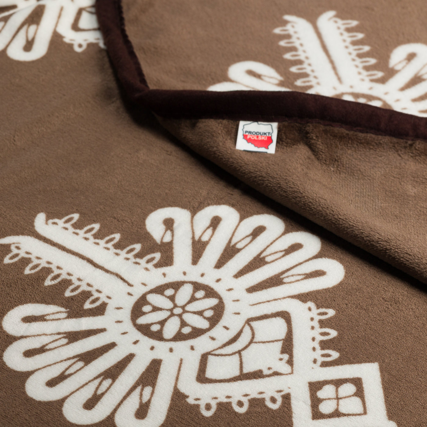 Metka Produkt Polski na kocu polarowym brązowym z białymi parzenicami