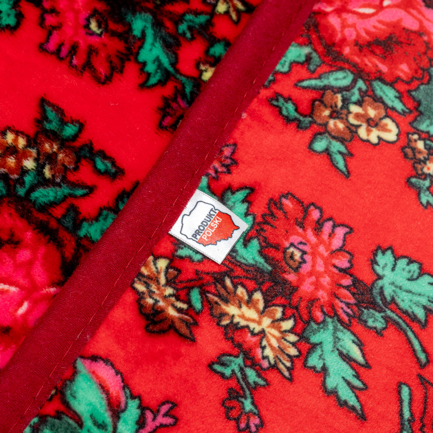 Metka Produkt Polski na czerwonym kocu polarowym kwiaty folklorowe detail wykończenia