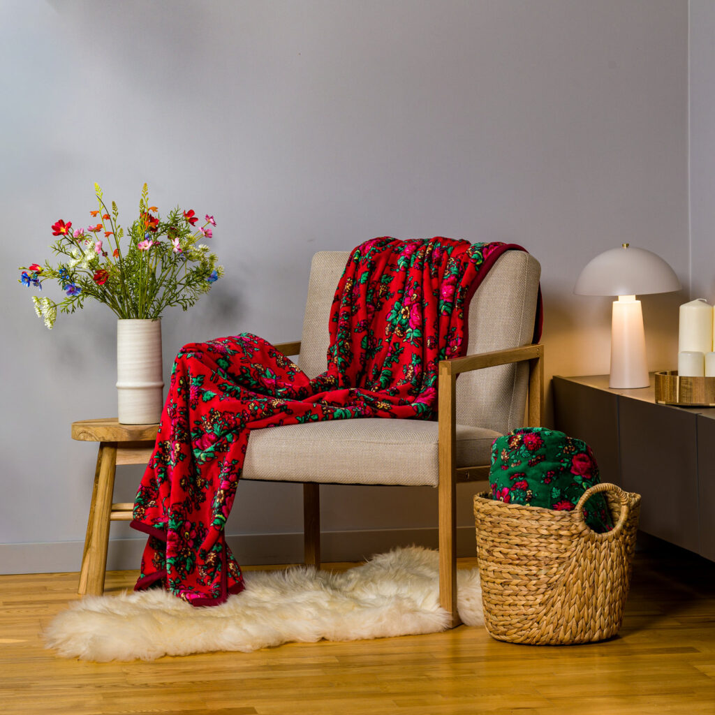 Czerwony koc kwiatowy folklorowy w nowoczesnym szarym wnętrzu na beżowym fotelu styling